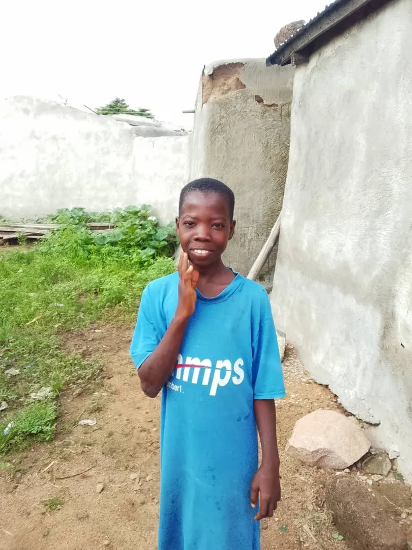 A smiling child in a blue T-shirt outside a home